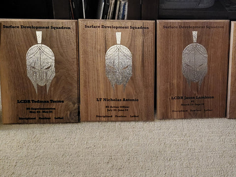 Three wooden going away plagues with engraved faces and names made by Mostad Works in San Diego.