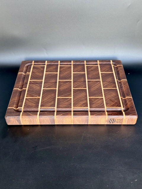 Angled top view of walnut brick pattern cutting board handmade in San Diego